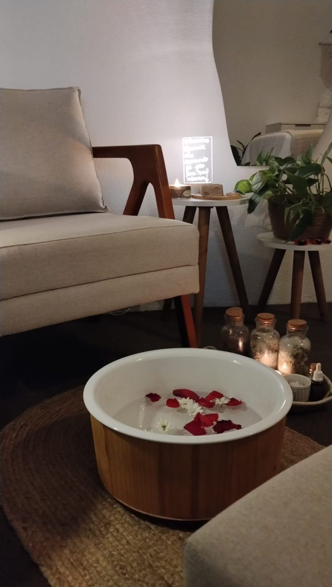 Cantinho do escalda-pés, com pétalas, velas e poltrona.